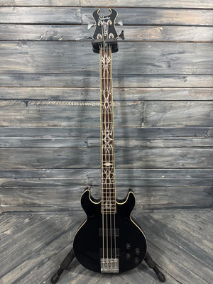 Black electric bass guitar on a wooden floor