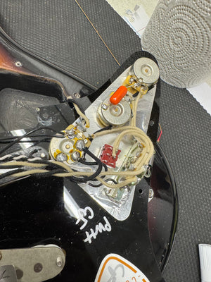 Close-up of a guitar's electronic components with visible wiring and labels.