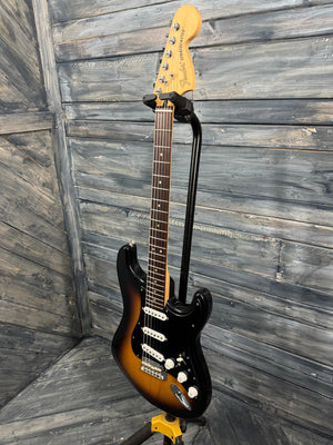 Electric guitar with a sunburst finish against a wooden background