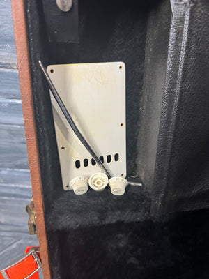 Close-up of a guitar amplifier with a control panel and cables.