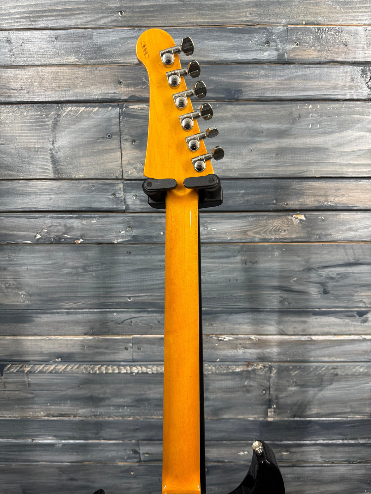 Guitar neck with tuning pegs against a wooden background