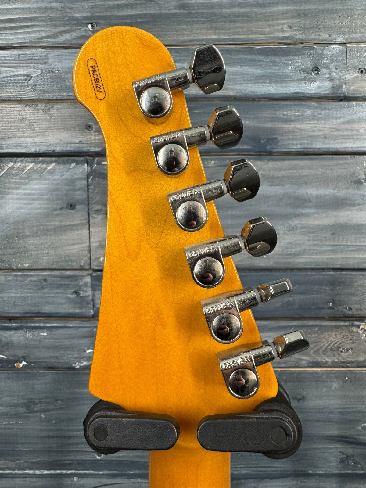Guitar headstock with tuning pegs on a wooden background