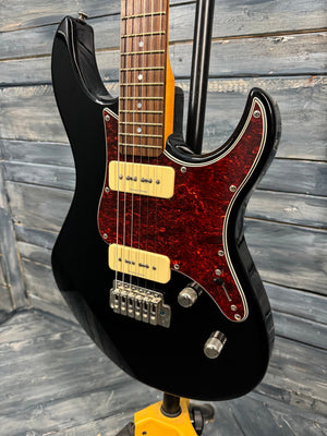 Black electric guitar with a red flame maple neck on a wooden background