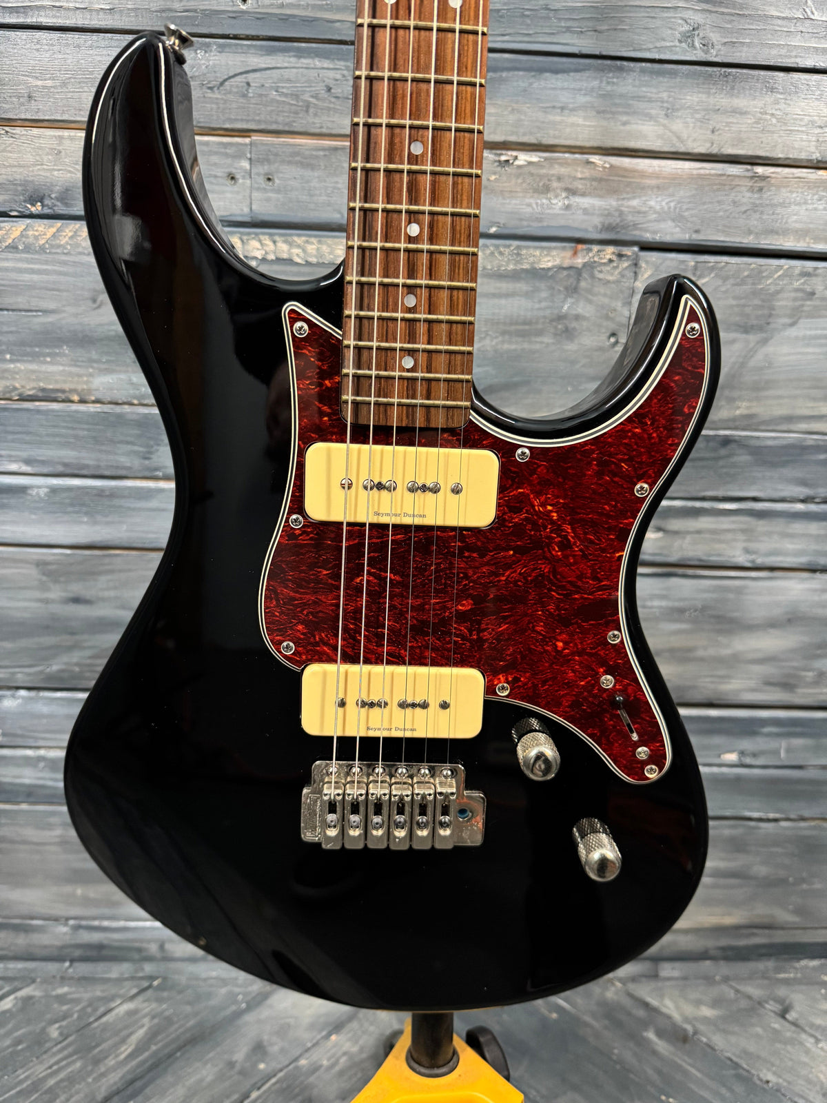 Black electric guitar with a red flame maple top on a wooden background