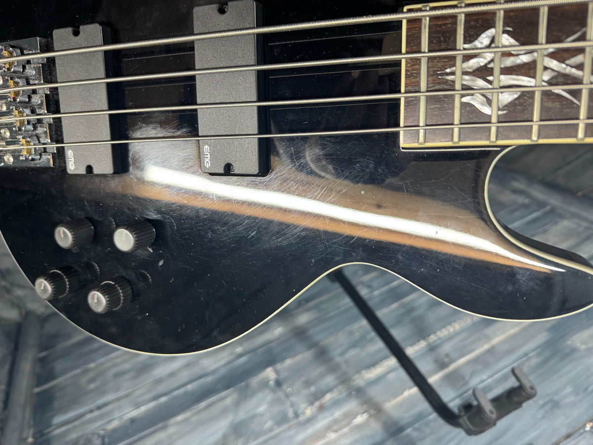 Close-up of a black electric bass guitar on a wooden surface