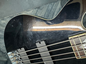Close-up of a black electric bass guitar on a reflective surface