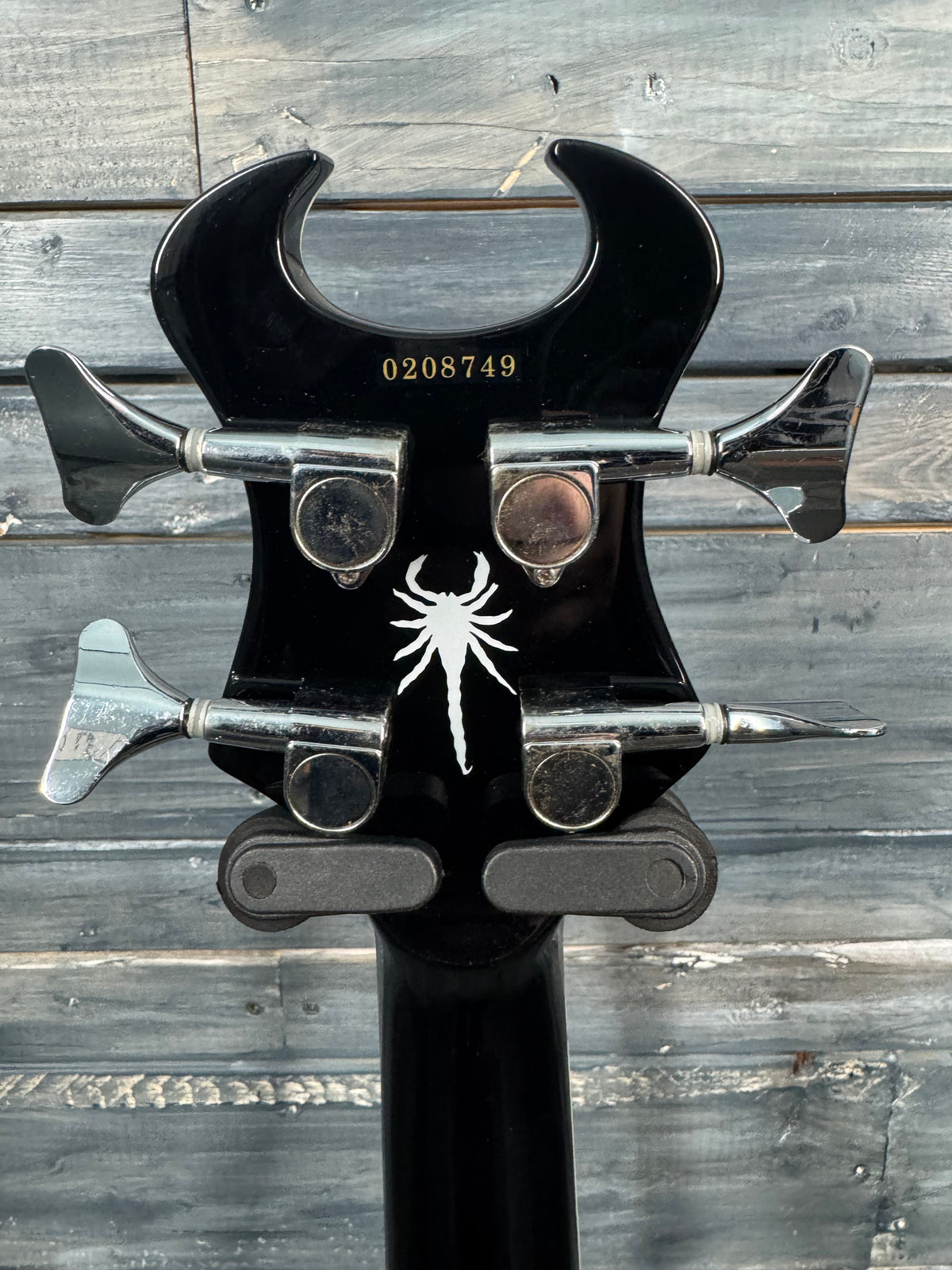 Guitar headstock with spider logo on a wooden background