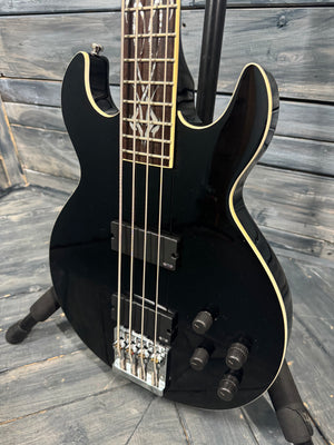 Black electric bass guitar on a wooden floor