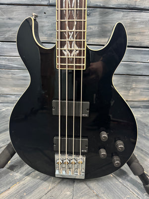 Black electric bass guitar on a wooden surface