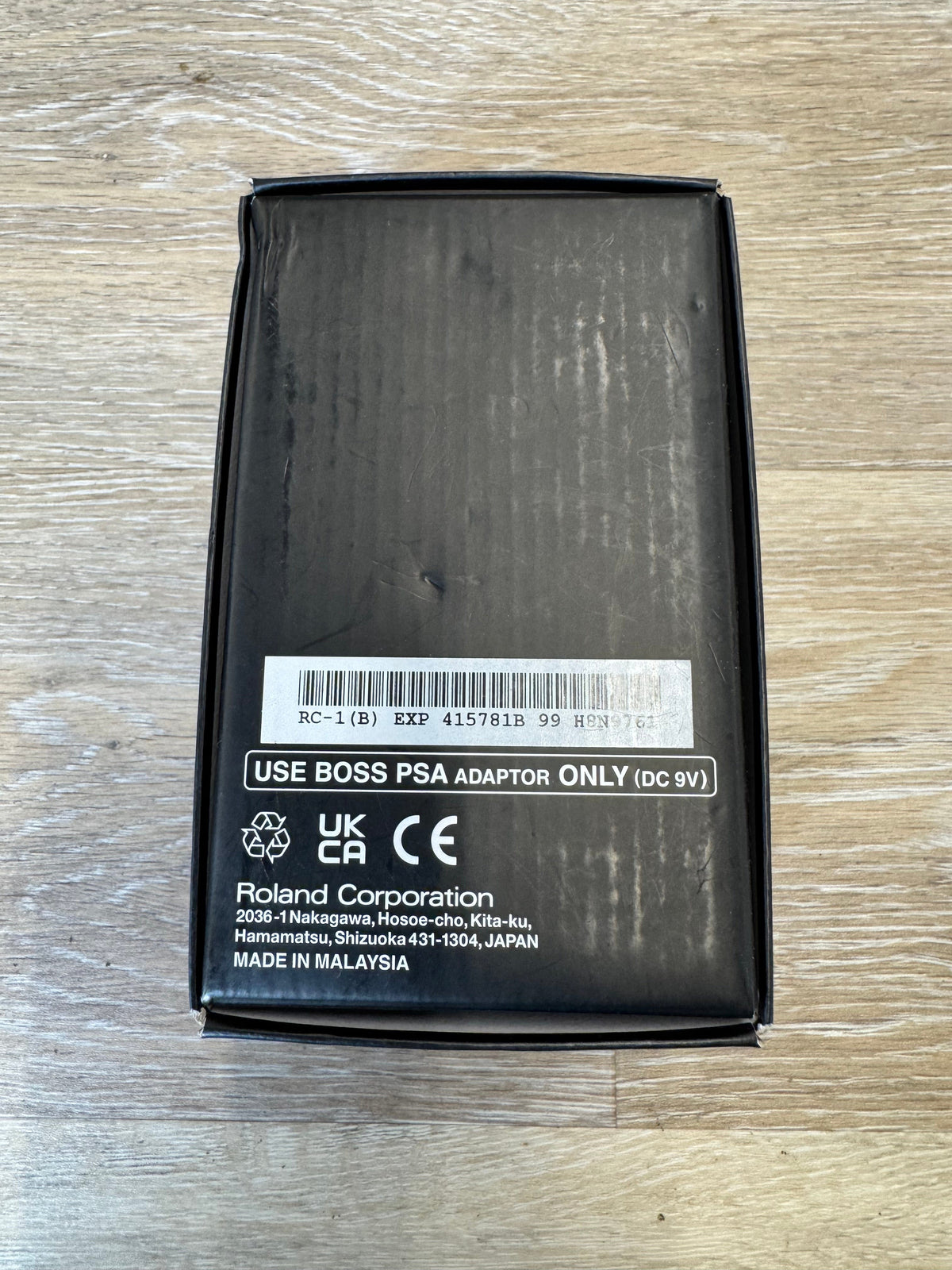 Black electronic device packaging with Roland Corporation label on a wooden surface