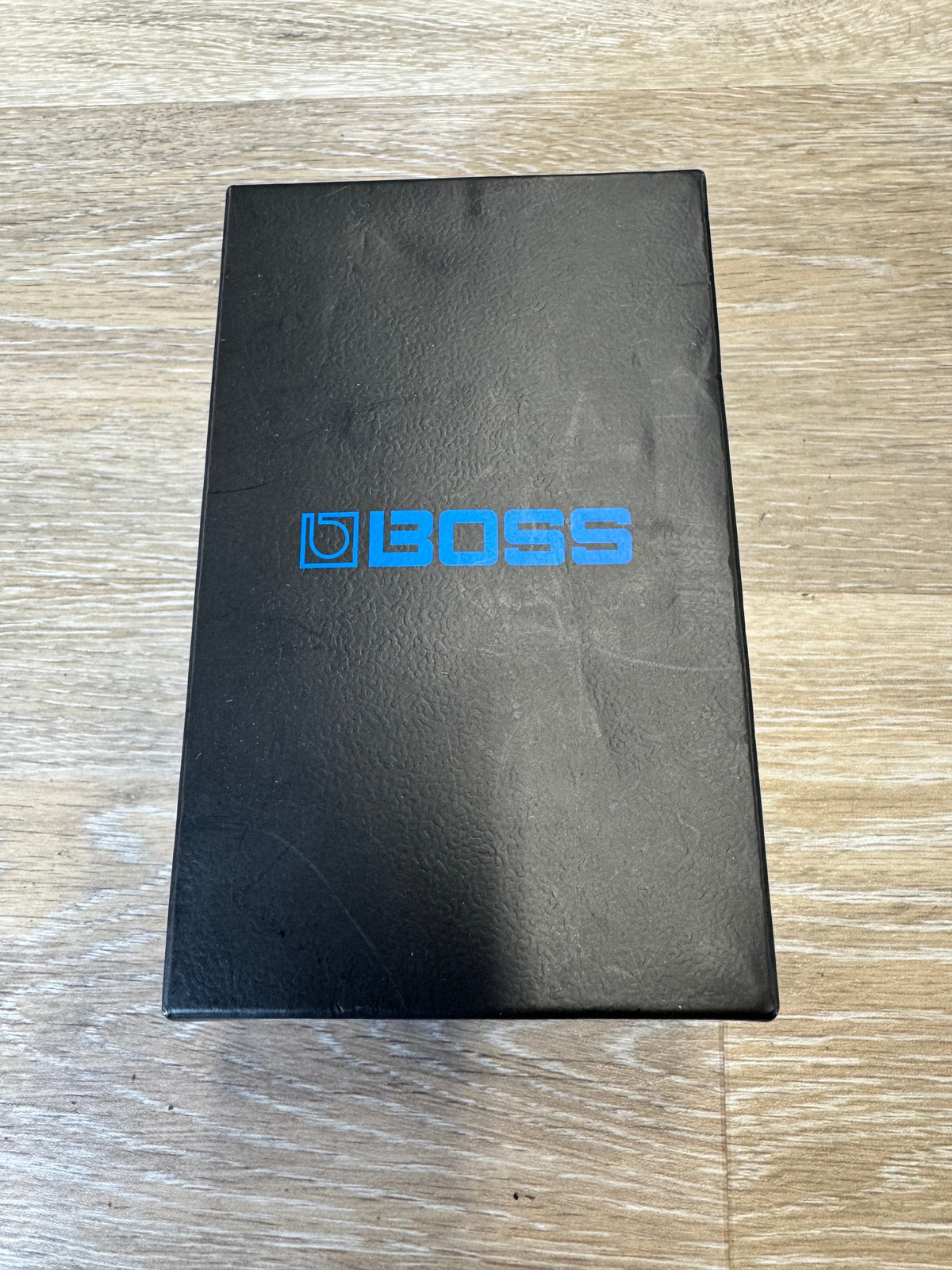 Black rectangular object with 'BOSS' branding on a wooden surface