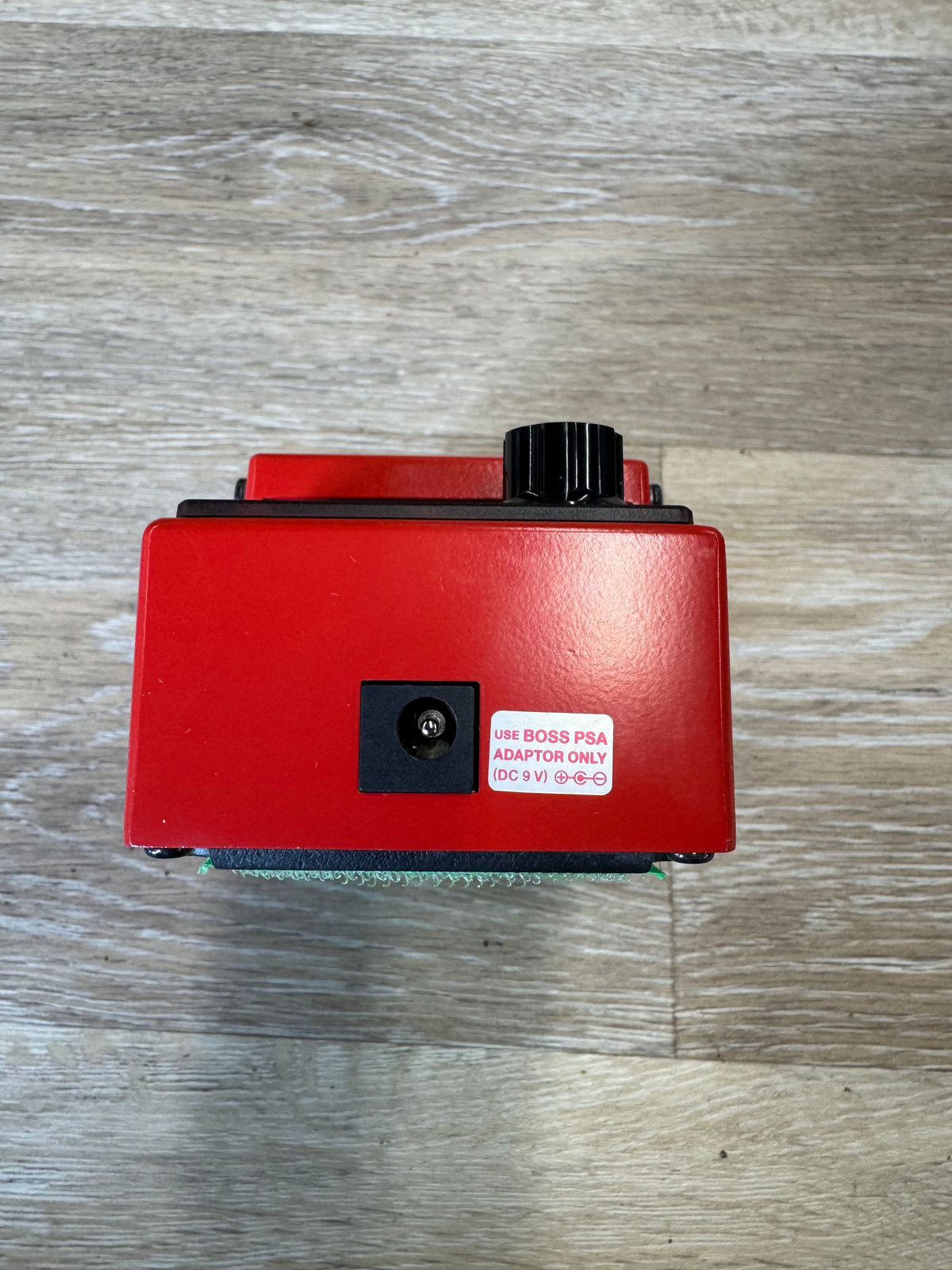 Red electronic device with a label on a wooden surface