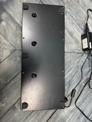 Black rectangular object with multiple holes on a wooden surface