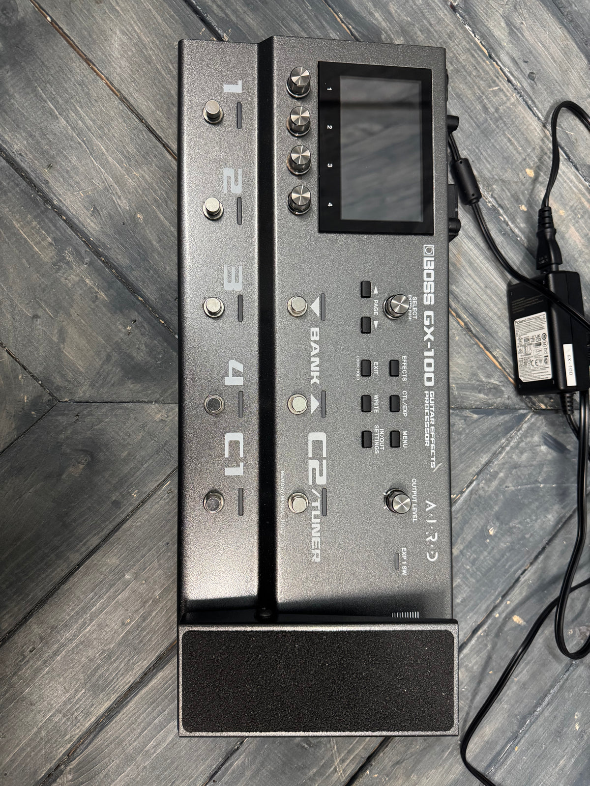 Gray electronic device with multiple buttons and a screen on a wooden surface