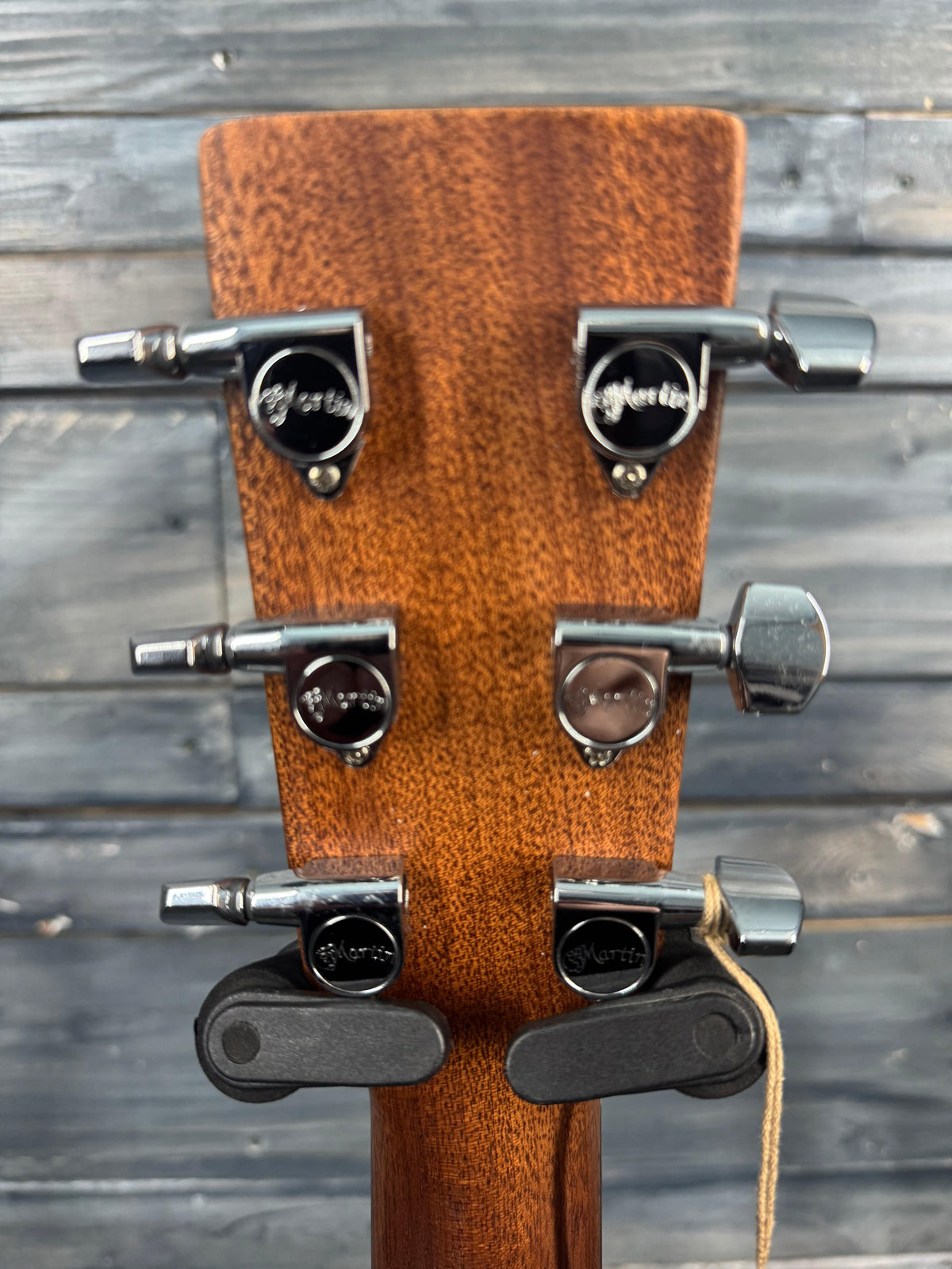 Close-up of a guitar headstock with tuning pegs against a wooden background