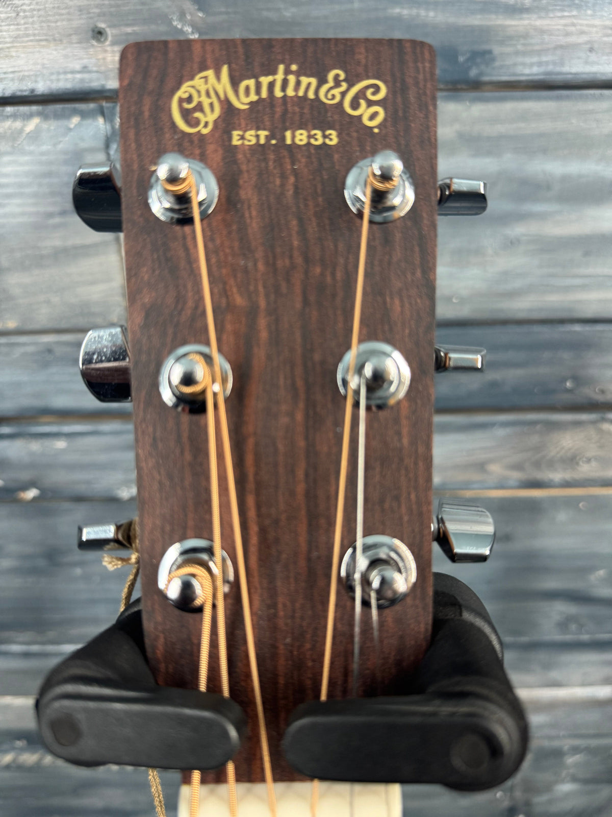 Guitar headstock with 'Martin & Co' branding against a wooden background