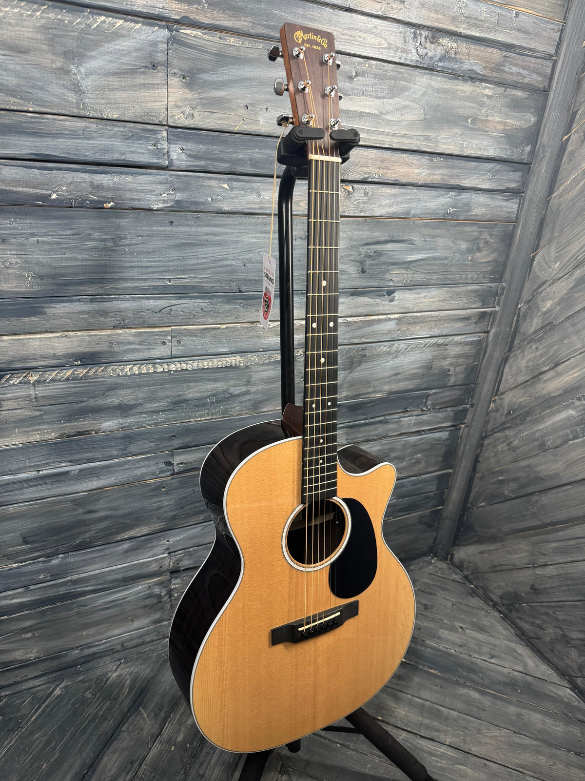 Acoustic guitar leaning against a wooden wall