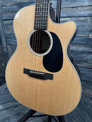 Acoustic guitar with a wooden finish leaning against a wooden wall.