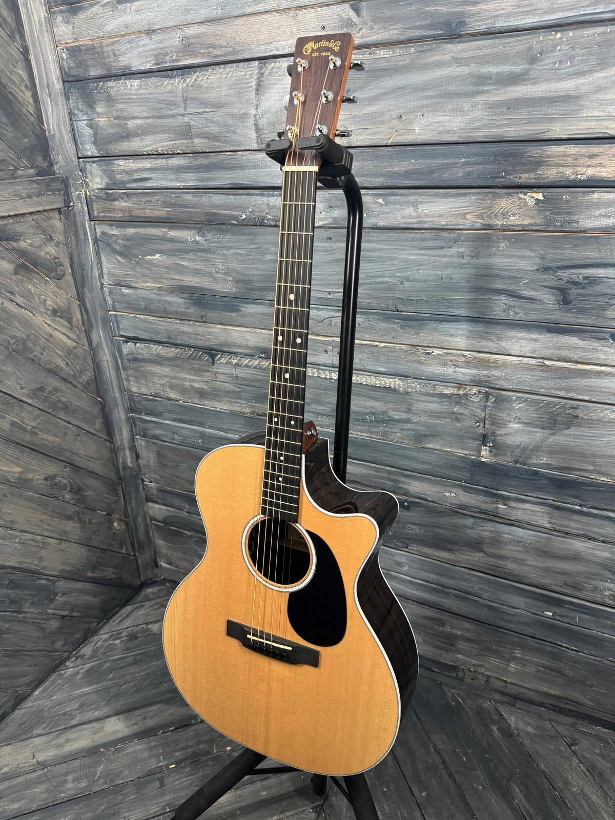 Acoustic guitar leaning against a wooden wall