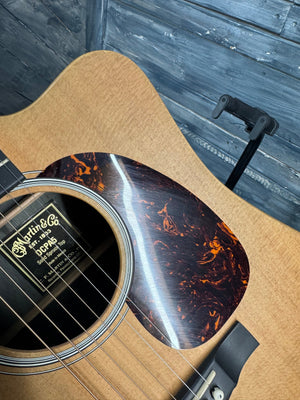 Close-up of an acoustic guitar with a visible brand label on a wooden surface.