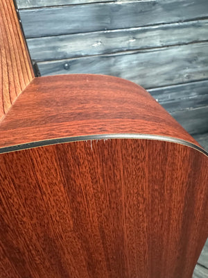 Close-up of a wooden guitar with a metal truss rod, against a rustic wooden background.