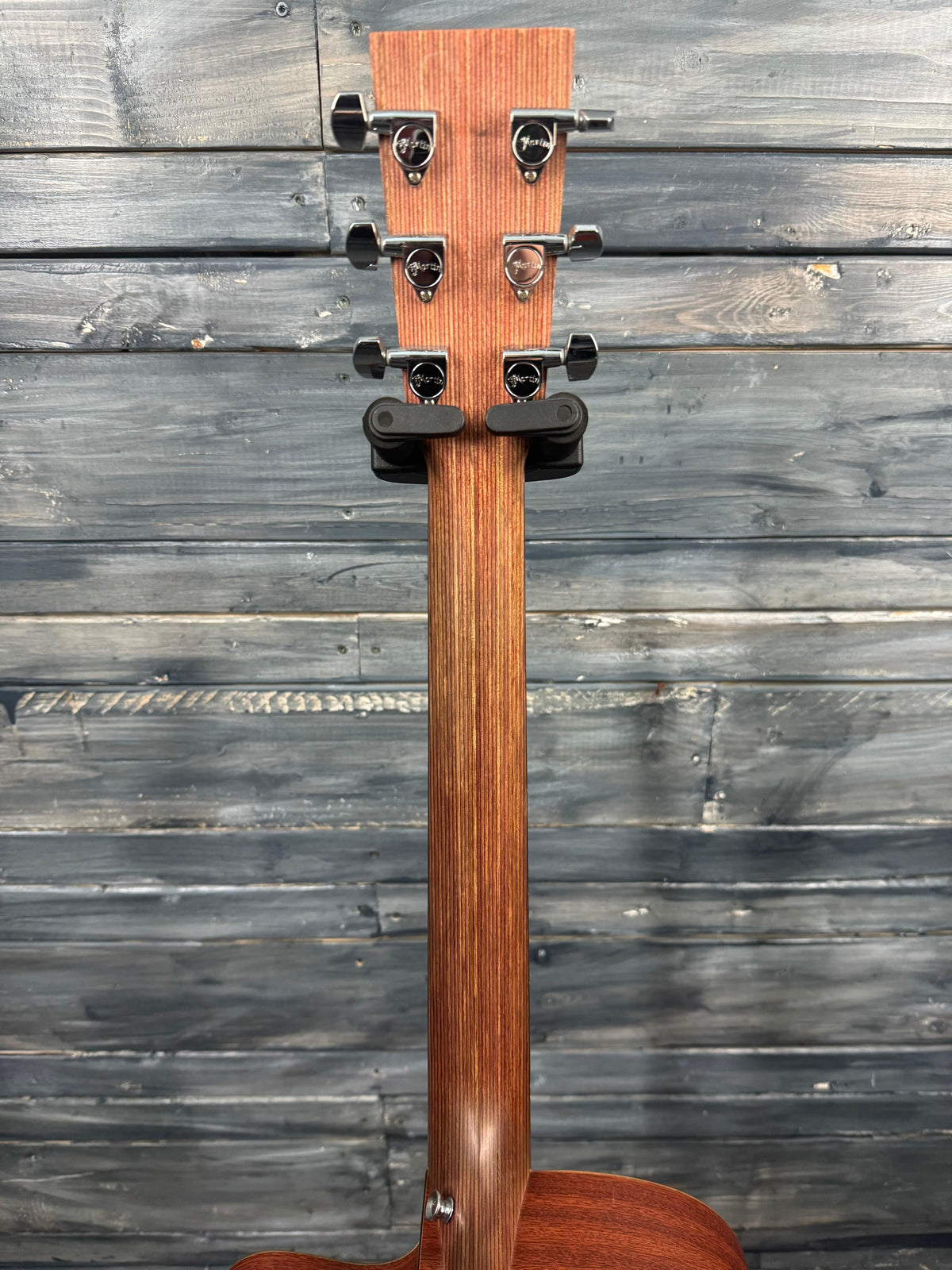 Wooden guitar neck with a strap against a wooden background