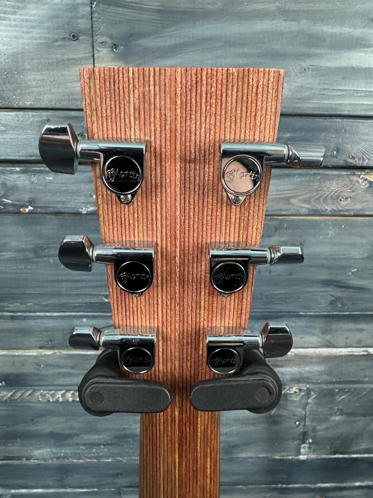 Wooden guitar wall hanger with metal hooks against a wooden background