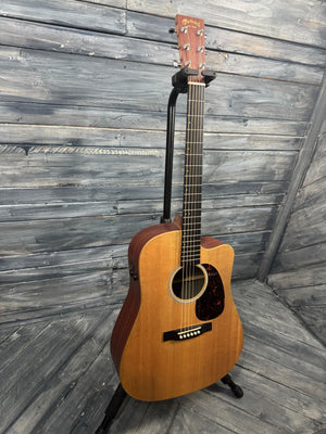 Acoustic guitar leaning against a wooden wall