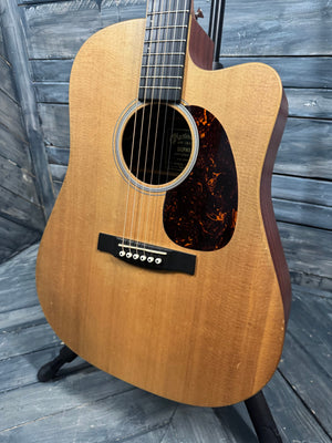 Acoustic guitar leaning against a wooden wall