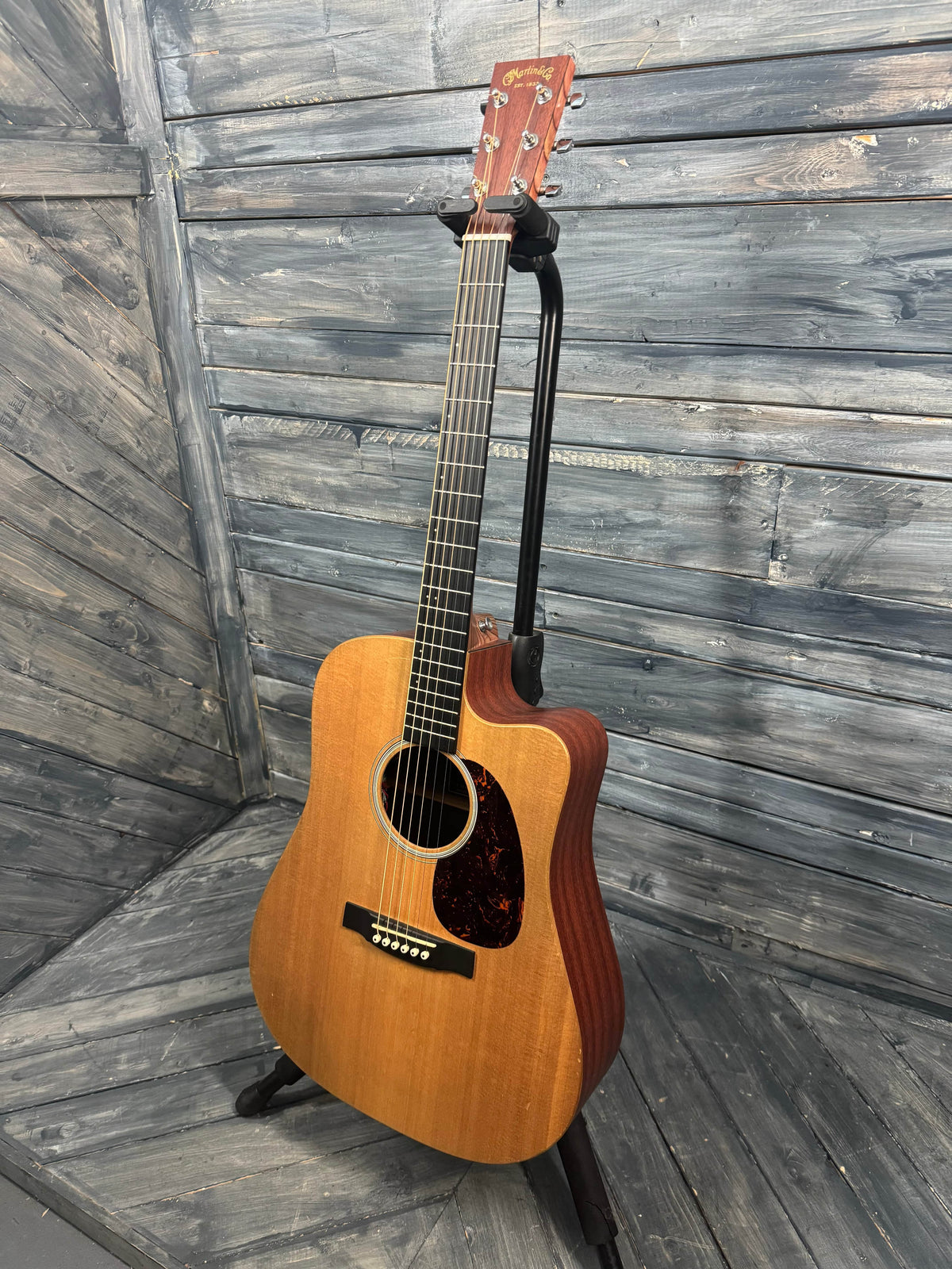 Acoustic guitar leaning against a wooden wall