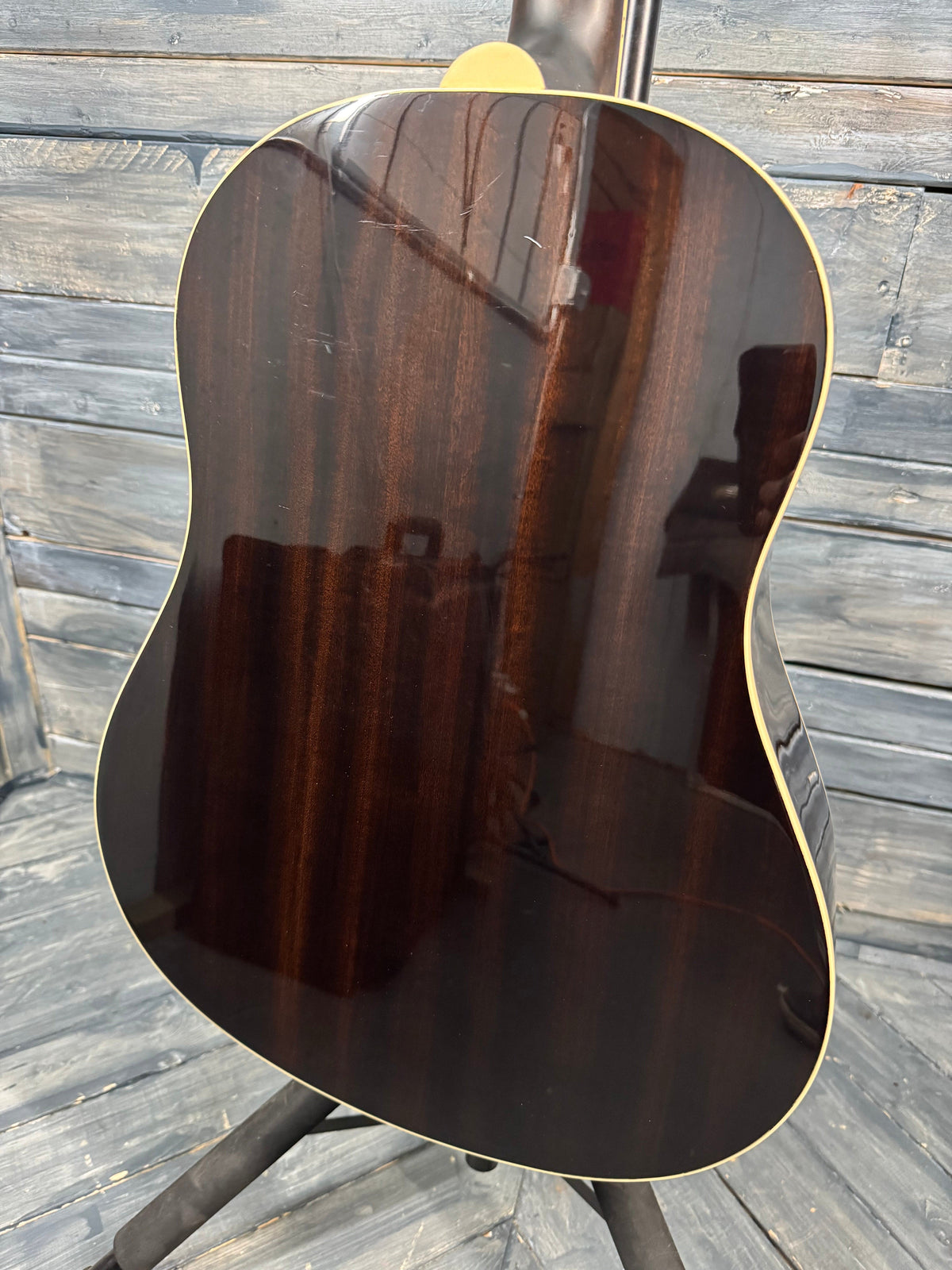 Close-up of a dark brown acoustic guitar body on a wooden surface