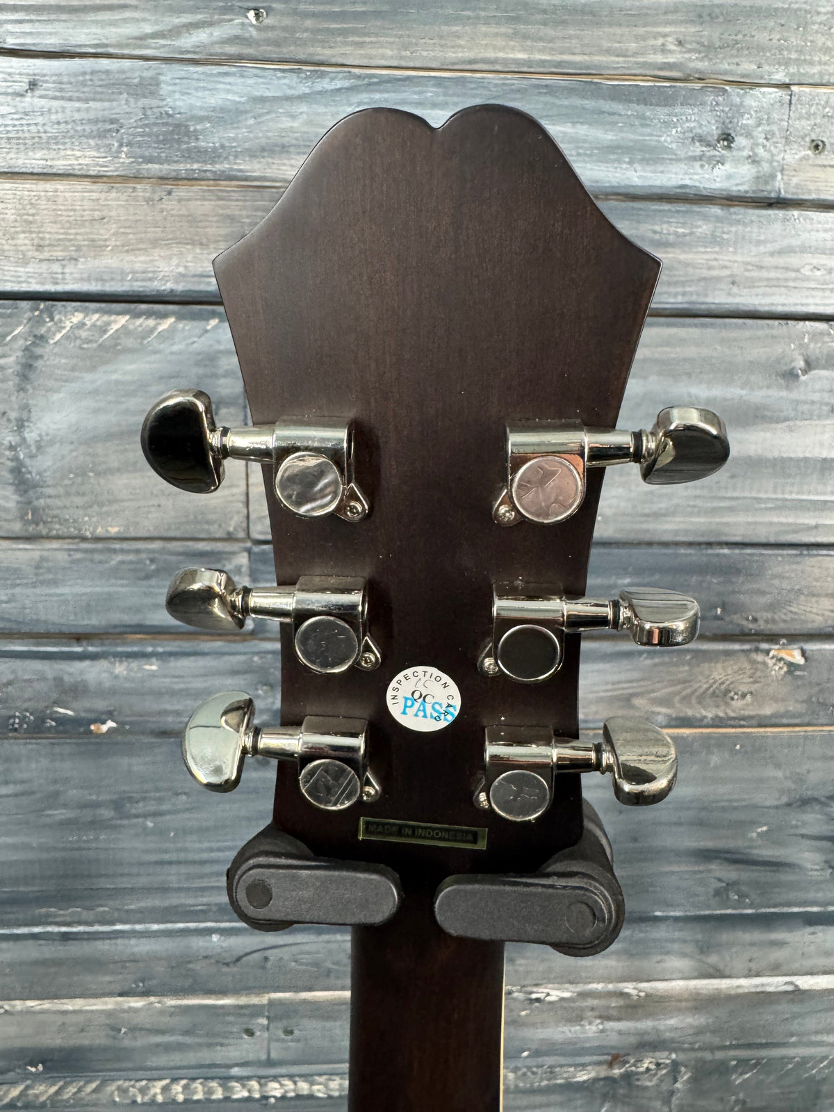 Close-up of a guitar's headstock with tuning pegs against a wooden background