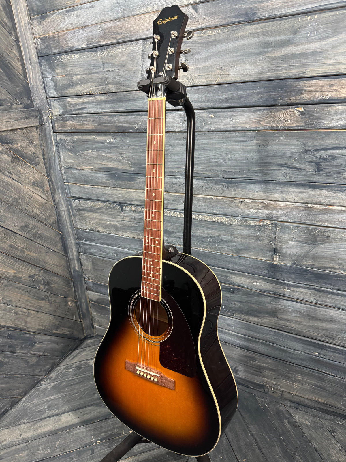 Acoustic guitar leaning against a wooden wall