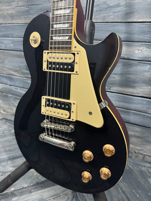 Black electric guitar with gold hardware on a wooden background