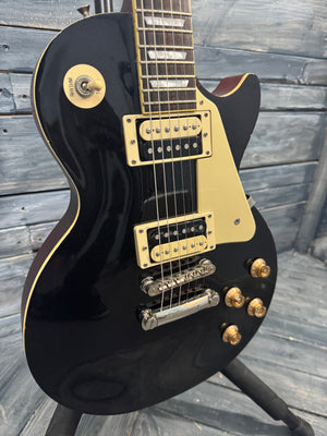 Black electric guitar with gold hardware on a wooden stand