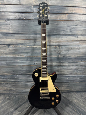 Black electric guitar with gold hardware on a wooden background