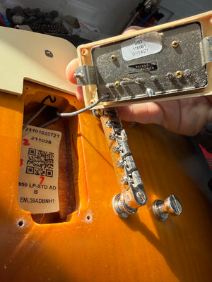 Close-up of a guitar's back with visible hardware and labels.
