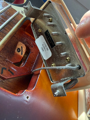 Close-up of a guitar pickup with visible wiring and label.
