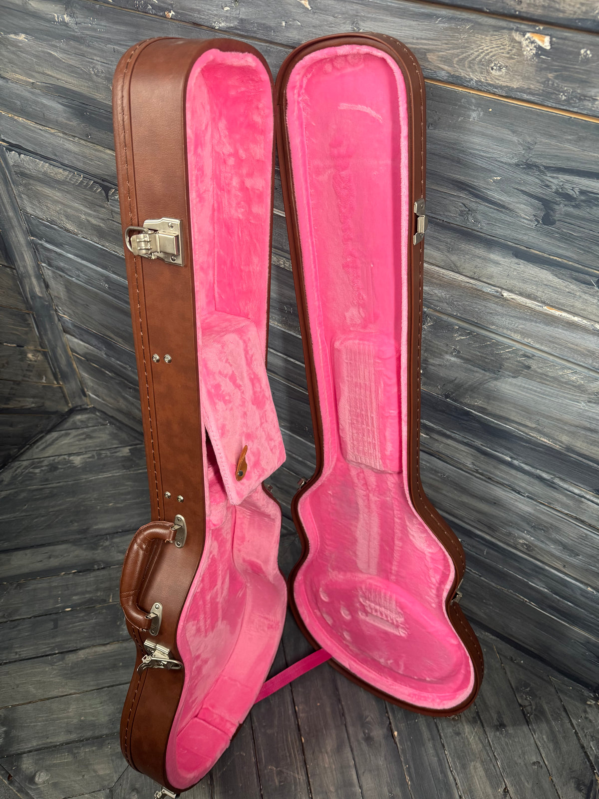 Pink guitar case with brown exterior on a wooden floor