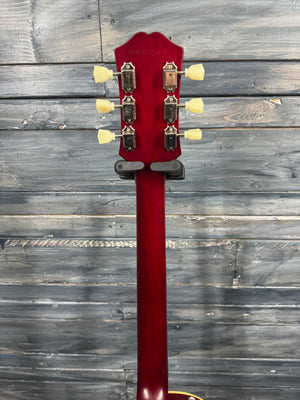 Red guitar neck with tuning pegs against a wooden background