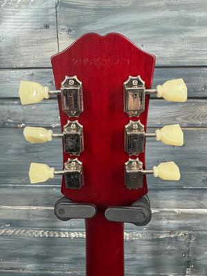 Red guitar headstock with tuning pegs against a wooden background