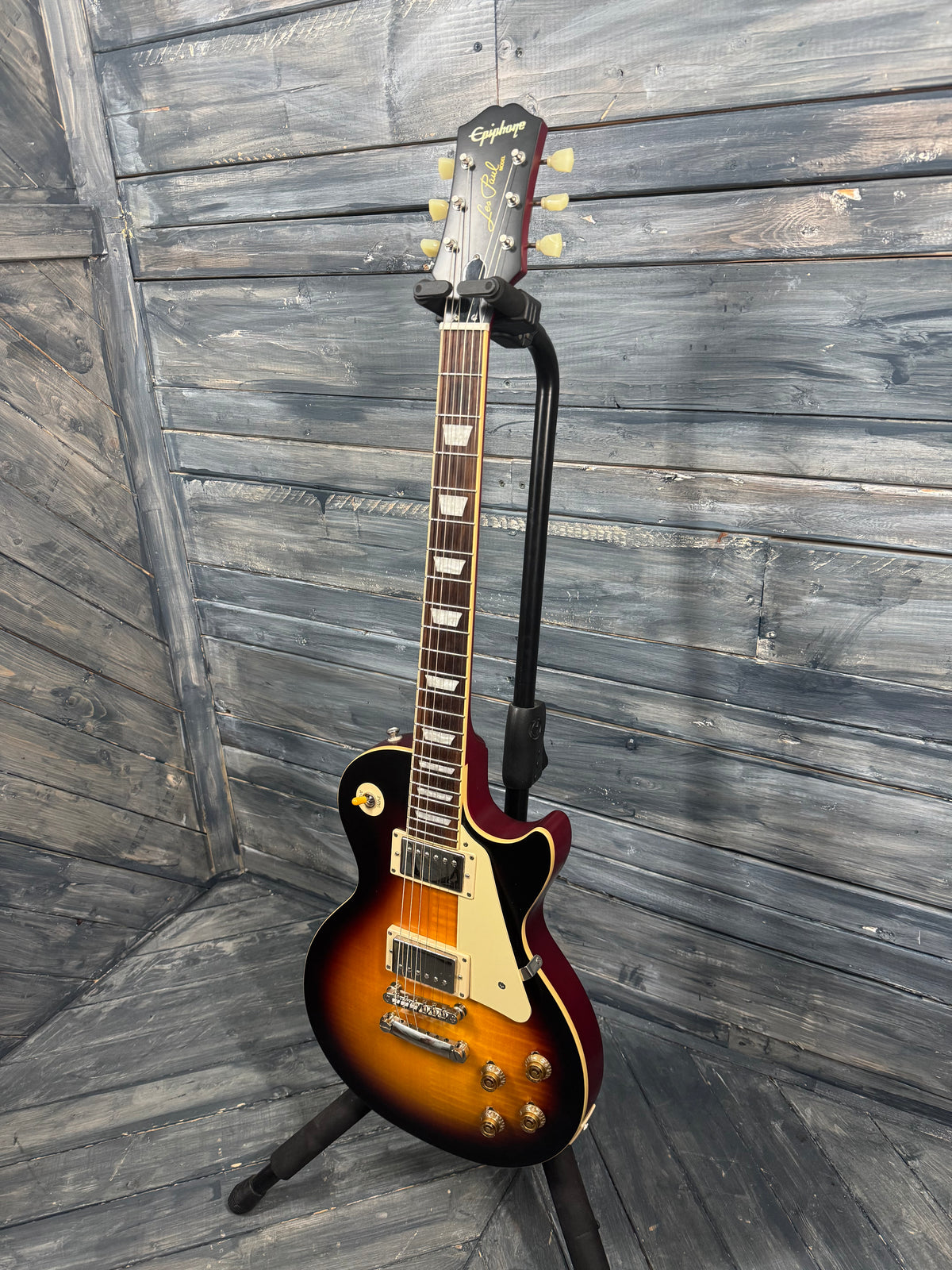 Electric guitar on a stand against a wooden wall