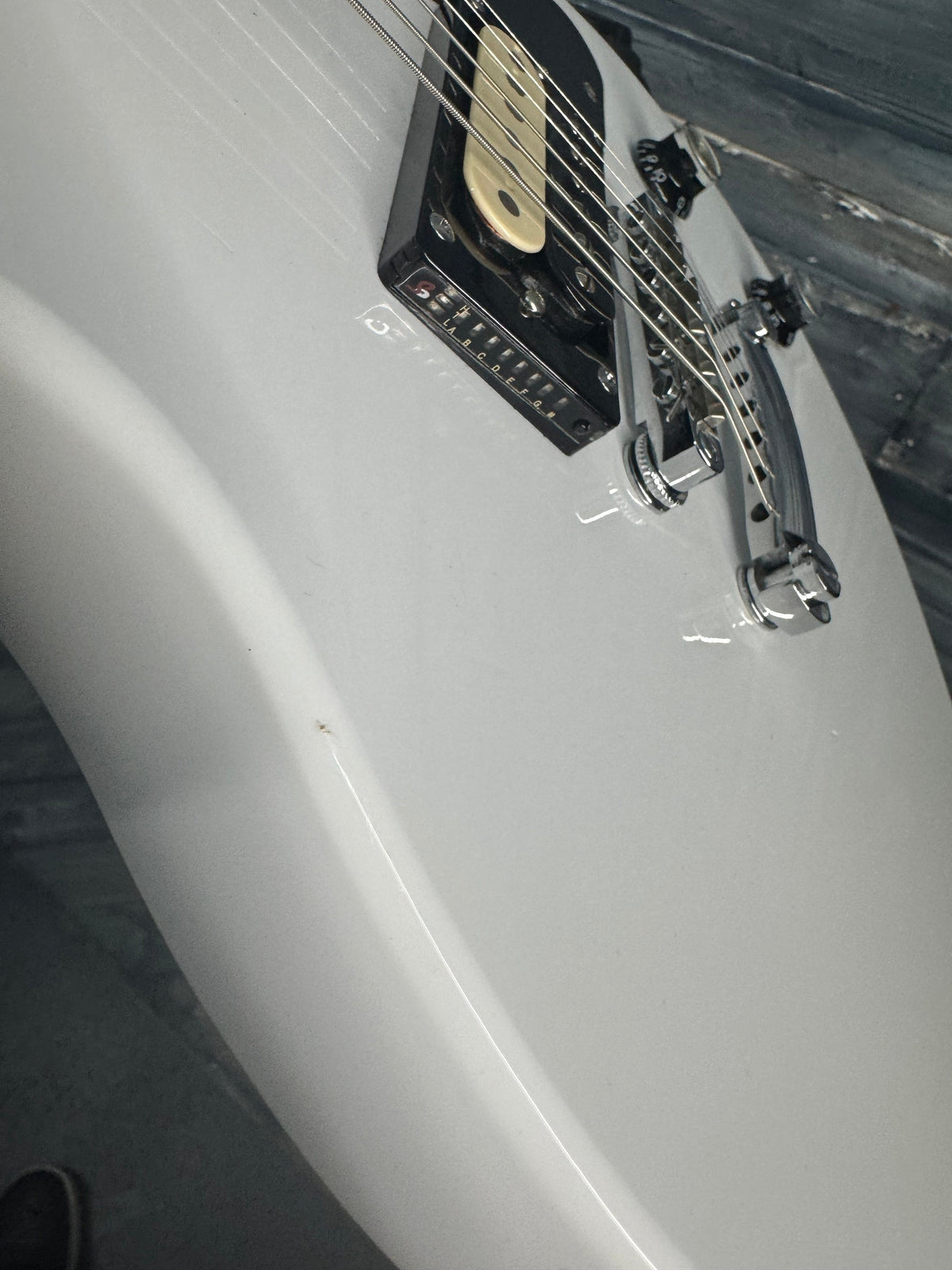 Close-up of a white electric guitar with a black pickguard and visible strings.