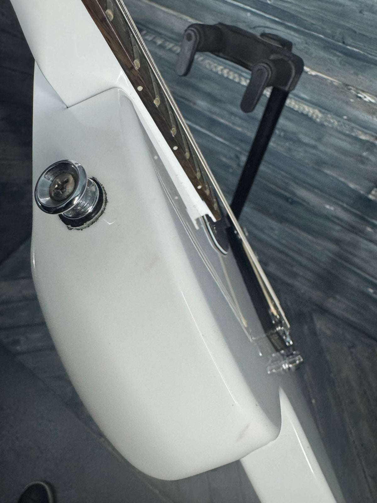 Close-up of a guitar neck with a white pickguard and black truss rod cover.