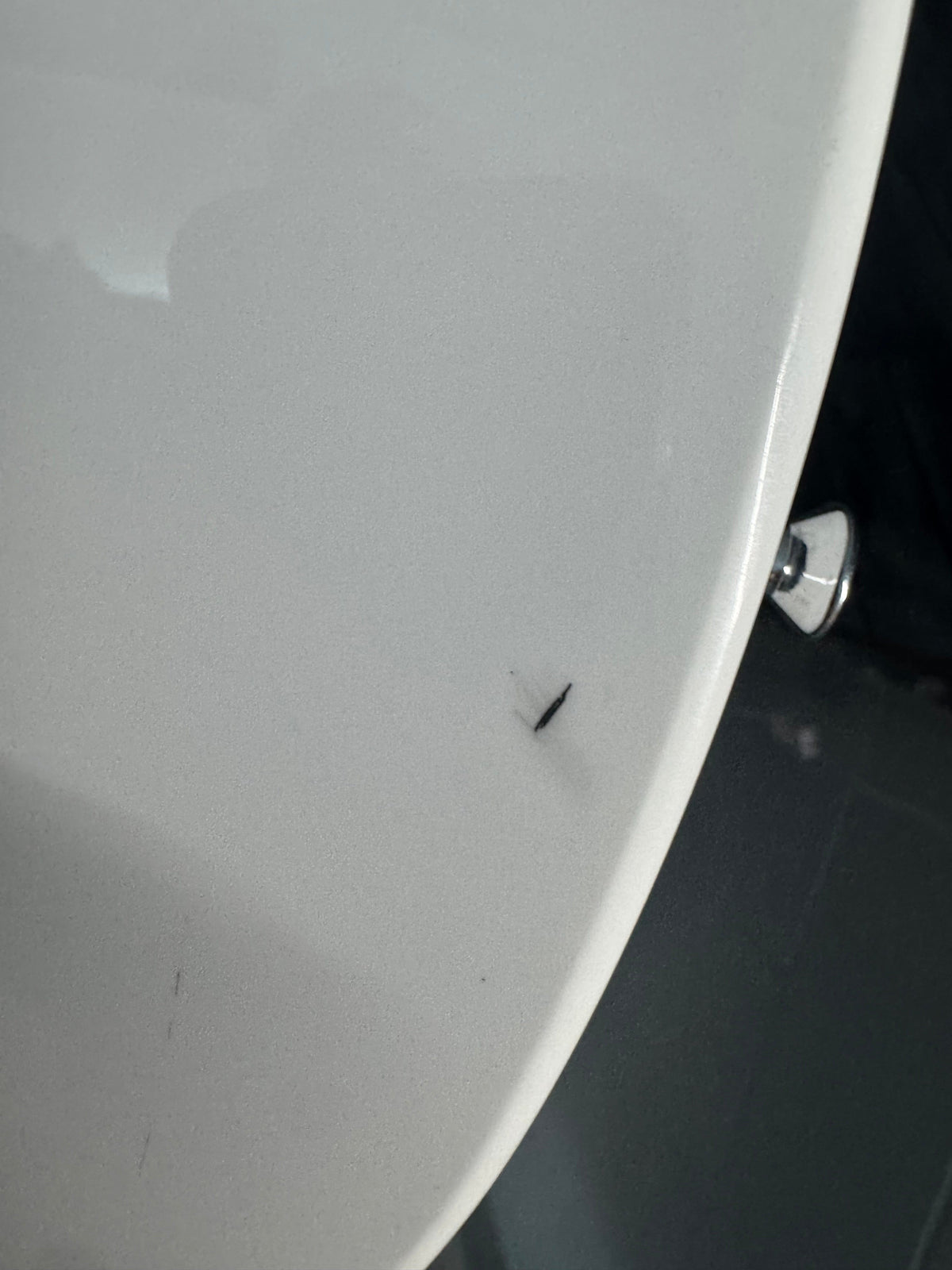 Close-up of a white surface with a small black object on it.