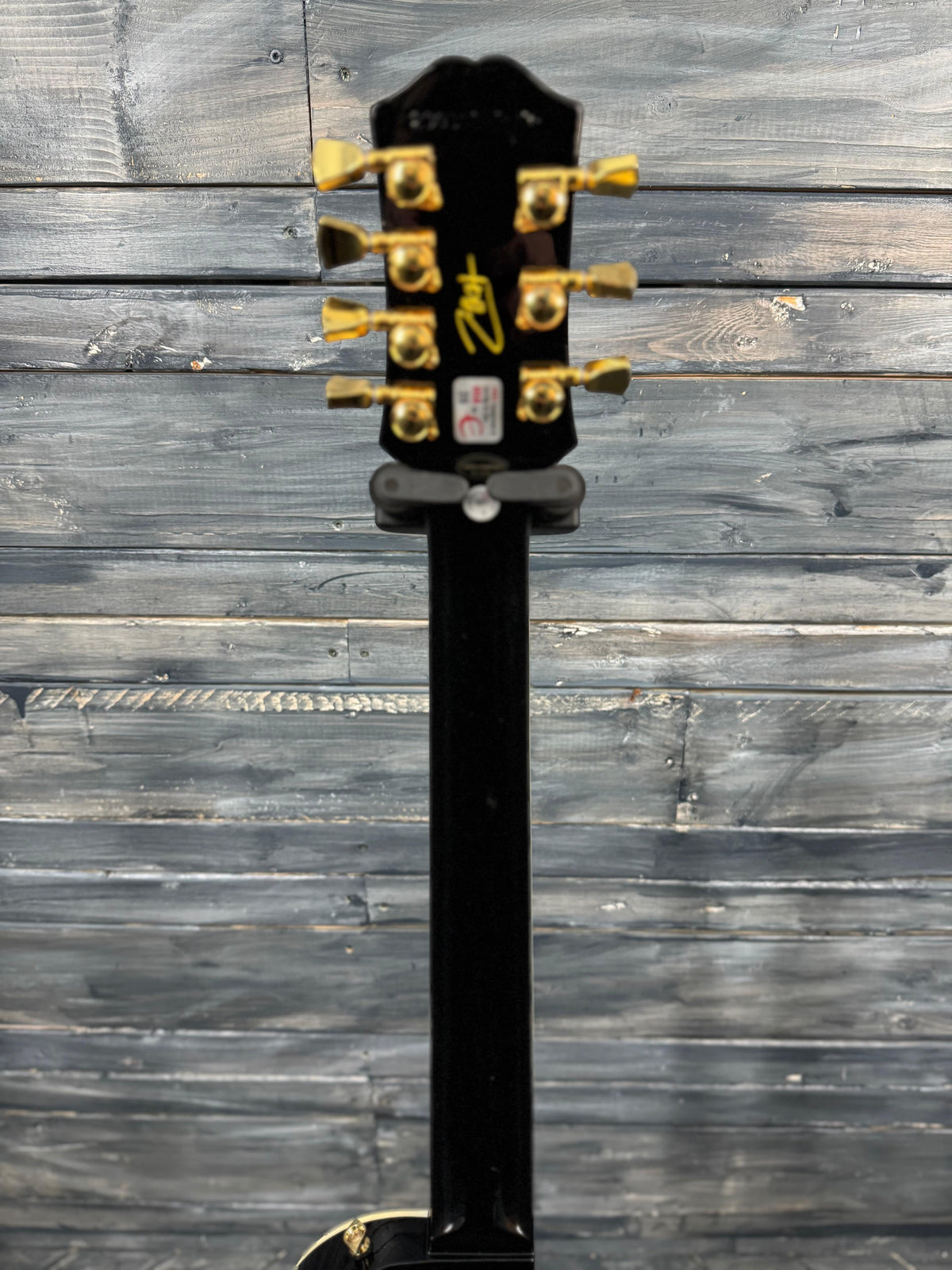 Guitar headstock with six tuning pegs on a wooden background