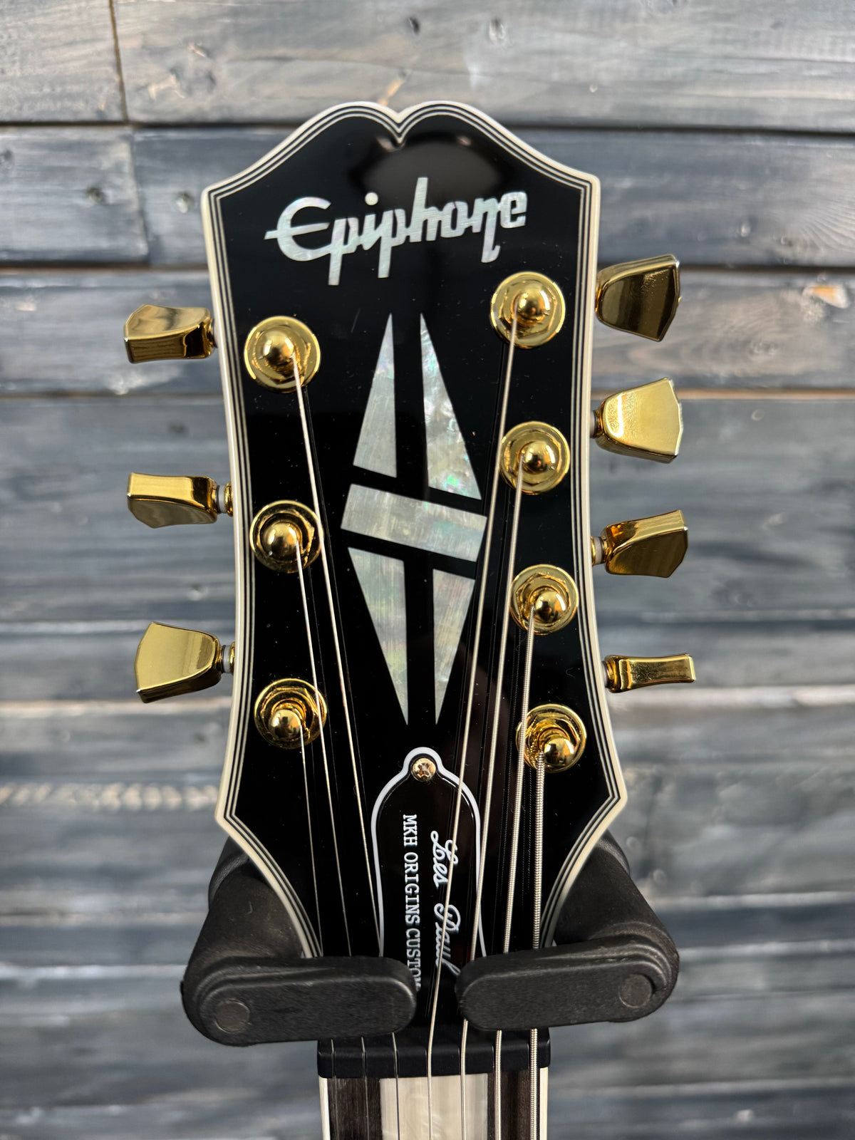 Guitar headstock with 'Epiphone' branding against a wooden background