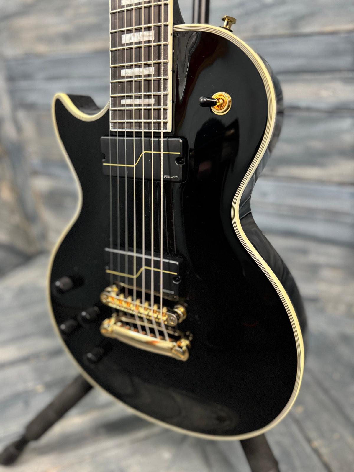 Black electric guitar with gold hardware on a wooden floor