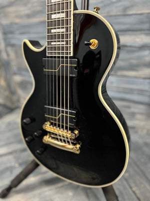 Black electric guitar with gold hardware on a wooden floor