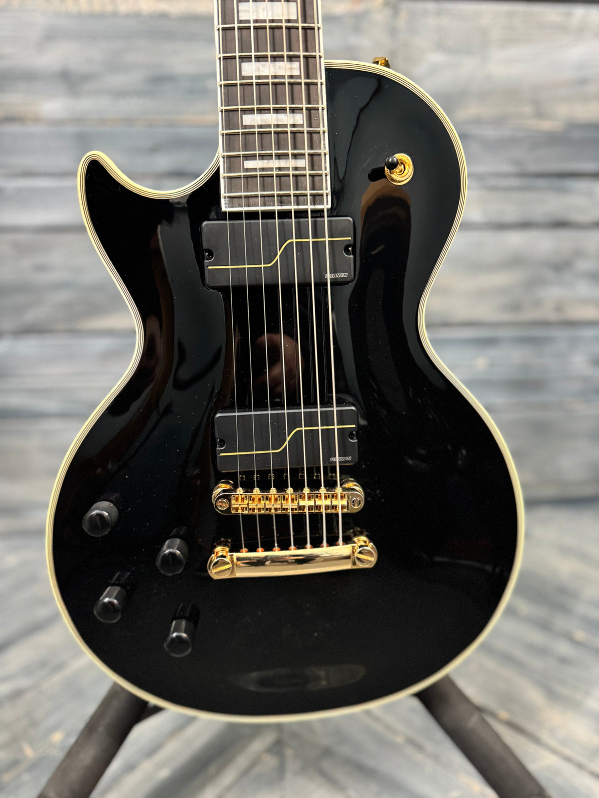 Black electric guitar with gold hardware on a wooden background